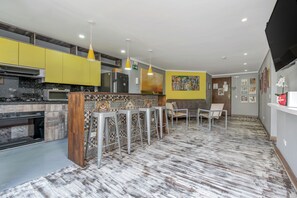 A modern kitchen with yellow cabinets, a marble countertop, and a central island with bar stools.