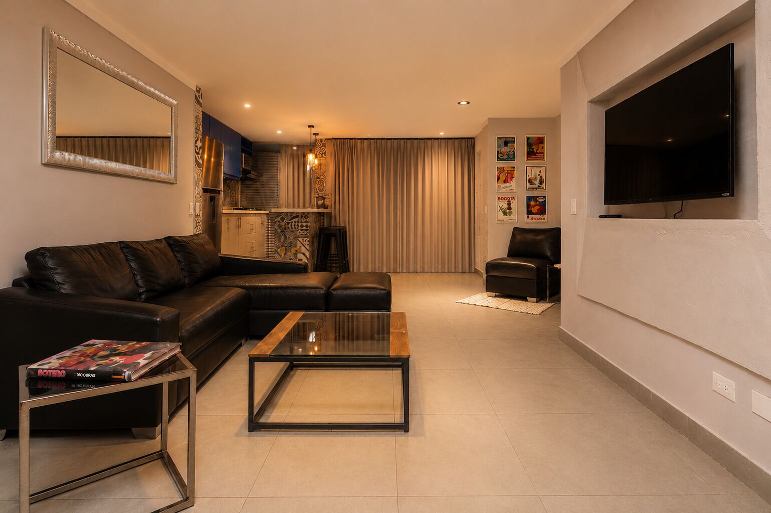 Una sala moderna con un sofá de cuero, una mesa de centro de vidrio y un televisor de pantalla plana montado en la pared.