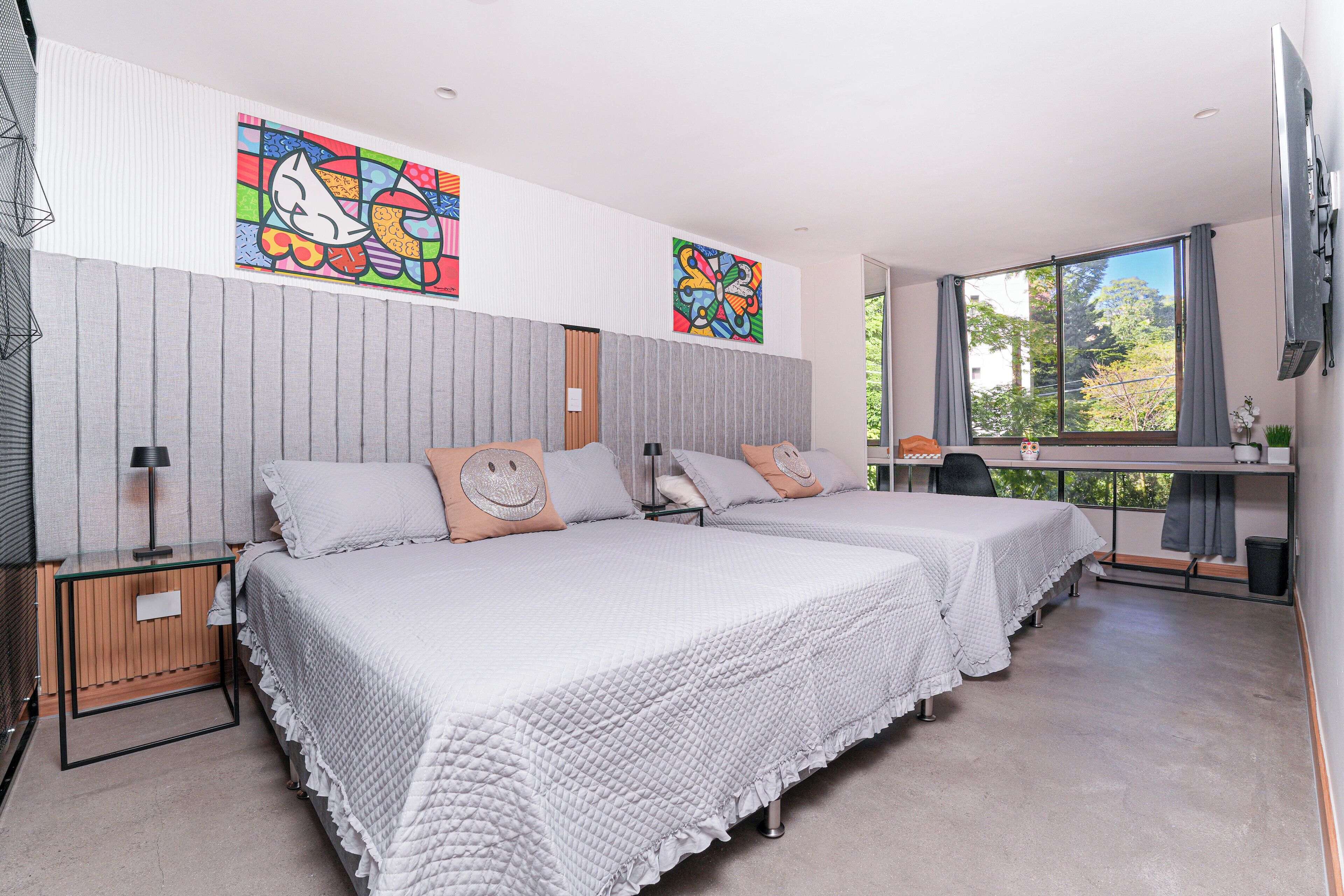 Une chambre d’hôtel moderne avec deux lits, un bureau et une grande fenêtre.