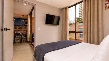 Habitación de hotel con cama, televisión, vista a la ciudad y kitchenette.