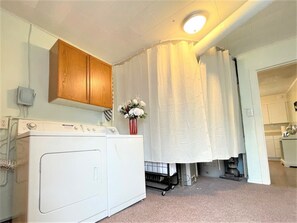 A laundry area with a washing machine, a cabinet, and a curtain. - High - Family Neighborhood, Pet Friendly (Van Wert)