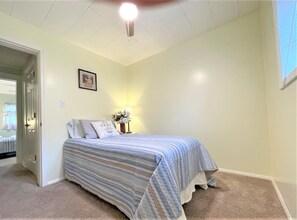 A bedroom with a bed, a nightstand, a framed picture on the wall, and a door leading to another room. - High - Family Neighborhood, Pet Friendly (Van Wert)