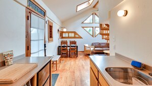 A compact kitchen with wooden countertops, a dining area with chairs, a built-in bench, and a large window. - Pet-Friendly Flagstaff Studio Cabin w/ Patio (Flagstaff)