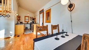 A modern kitchen with wooden cabinets, a dining area with a table set for two, and a staircase with a wooden railing. - Pet-Friendly Flagstaff Studio Cabin w/ Patio (Flagstaff)