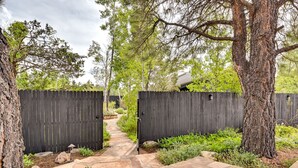 A stone pathway leading to a wooden gate, surrounded by greenery and trees. - Pet-Friendly Flagstaff Studio Cabin w/ Patio (Flagstaff)