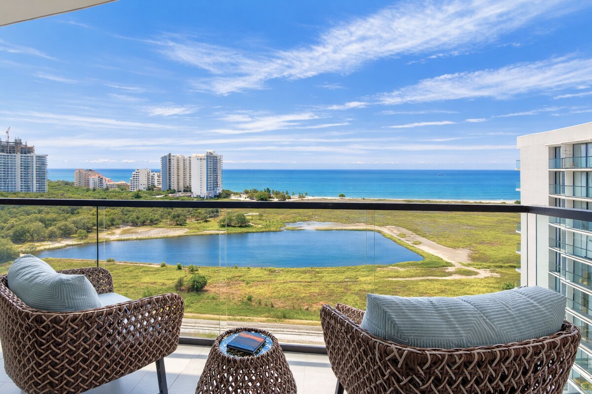 A balcony with wicker chairs and a view of a lake and cityscape.