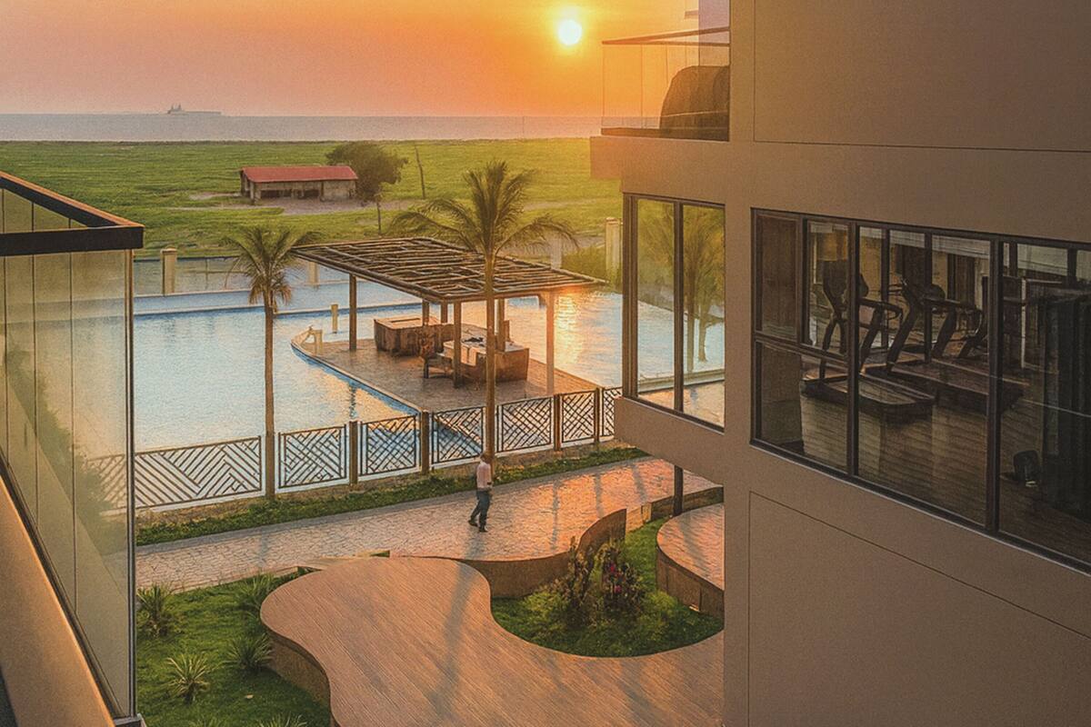 A modern hotel with a rooftop pool, a view of the sunset, and a distant ship on the horizon.