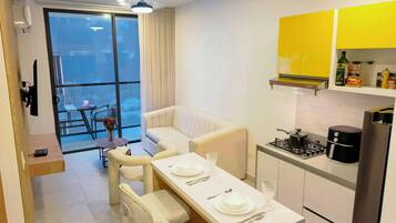 A modern kitchen with white cabinets, a dining table set for four, and a balcony with a view.