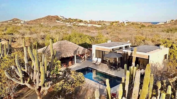 Ein modernes Haus mit Pool, umgeben von Kakteen.