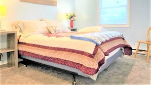Une chambre à coucher avec un lit, une table de chevet, une chaise et une fenêtre.