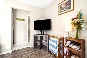 A room with a television on a stand, a bookshelf with books, a framed picture on the wall, and a sign with the word 'FAITH'. - Pontiac - Secluded Backyard, Pet Friendly (Fort Wayne)