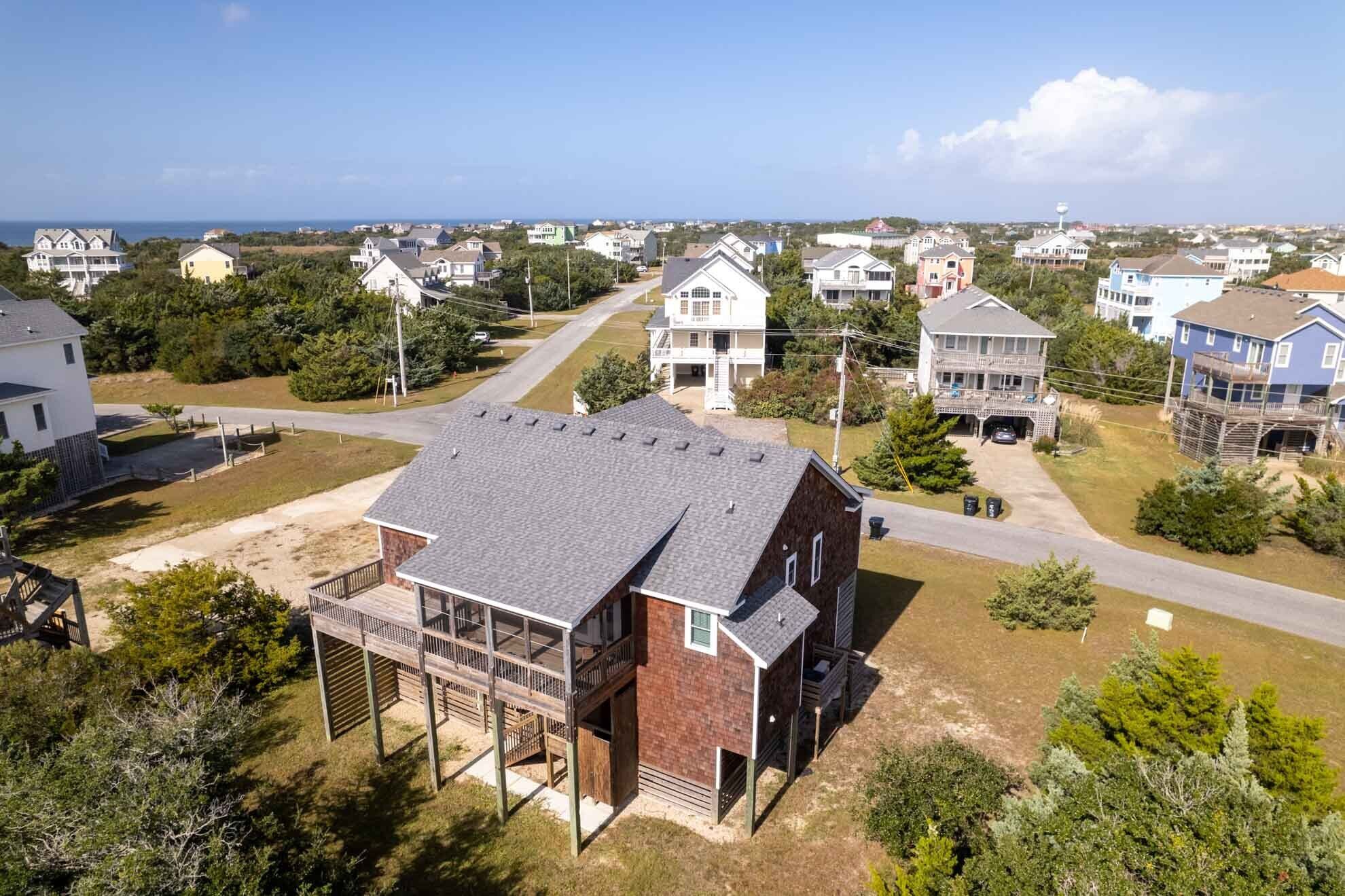A residential area with houses, a wooden deck, and a clear view of the ocean.