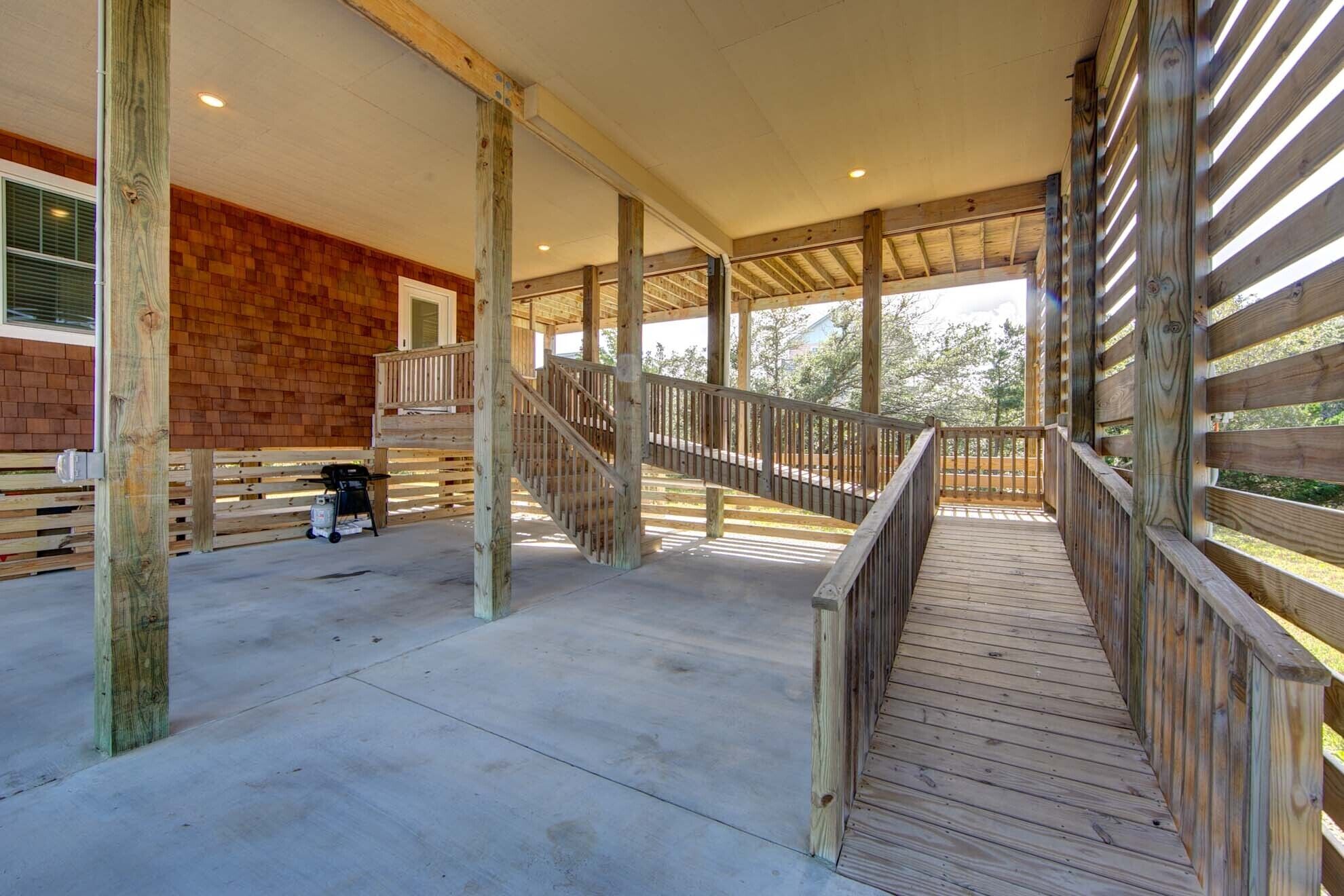 A covered outdoor area with a wooden deck, a staircase, and a brick wall.