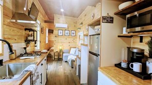 A compact kitchen with wooden walls, a central island, and a coffee machine.
