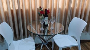 A round glass table with two white chairs, a bottle of wine, and two wine glasses. - Hotel Arabian (Lima)