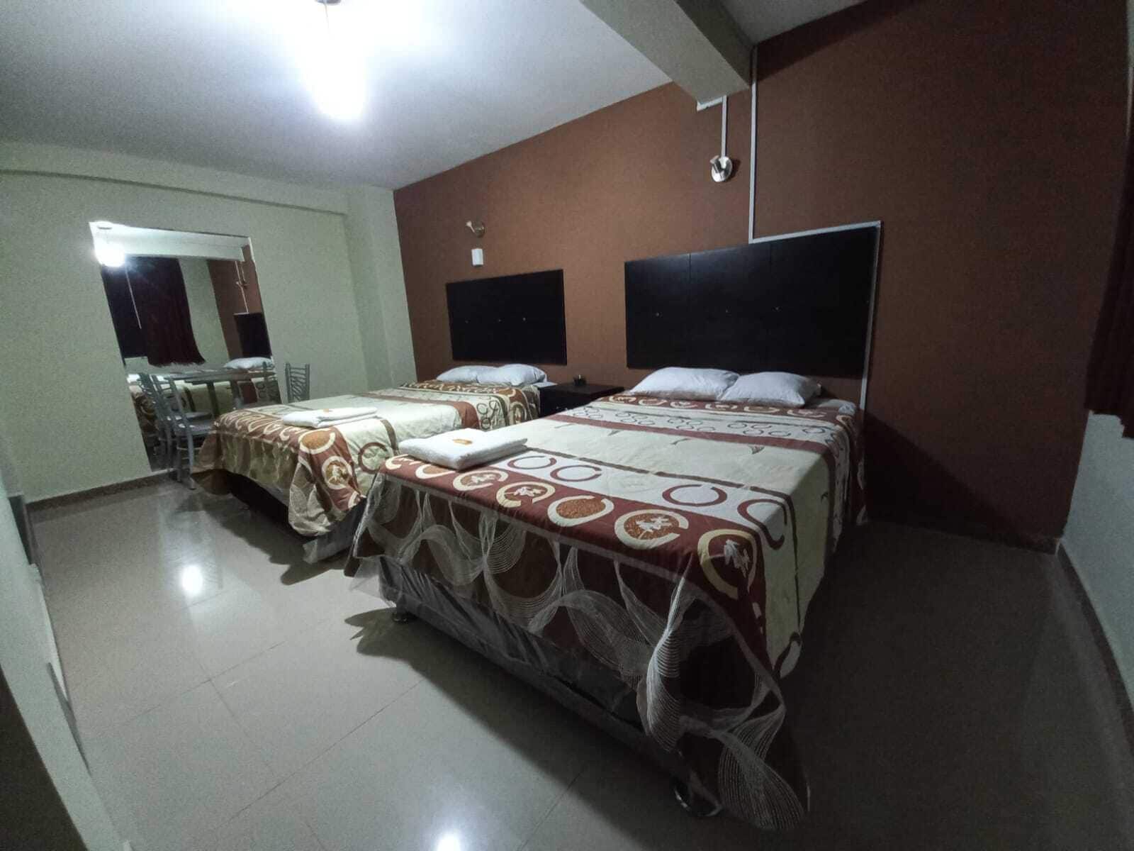 A hotel room with two beds, a desk, and a mirror.