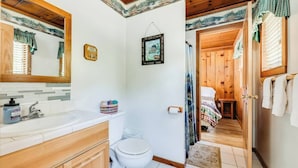 Un baño con tocador de madera, inodoro y zona de ducha.
