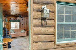 L’intérieur d’un chalet chaleureux, avec une façade en bois, une porte verte, une fenêtre à carreaux et un mur en bois rustique.