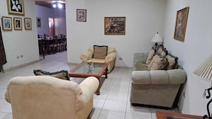 A living room with two sofas, a coffee table, and a dining area in the background. - Kartagus Futura (San Salvador)