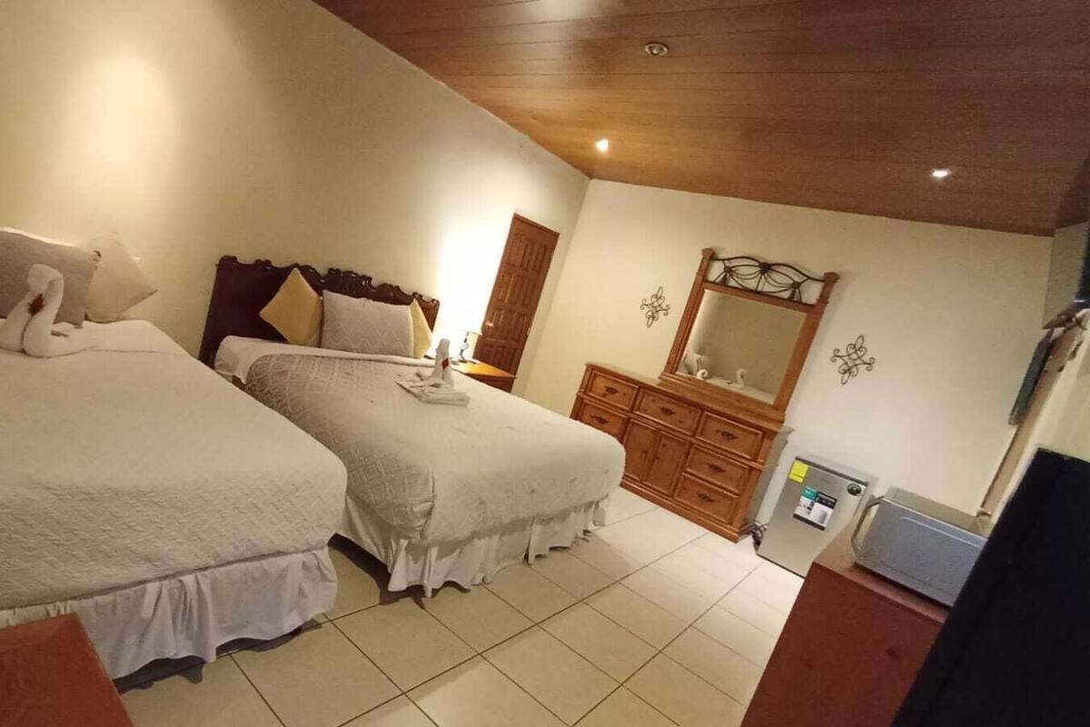 A bedroom with two beds, a dresser, a mirror, and a desk.