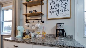 A kitchen with granite countertops, a coffee maker, and a quote on the wall. - Game Room-Deck-Coffee Bar (Englewood)