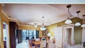 Uma sala de estar espaçosa com área de jantar, janelas amplas e vista para a cidade.