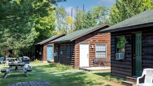 Tunnelmallinen mökki, jossa on kuisti, ruokailutila ja pieni ulkona oleva oleskelualue.