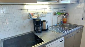 A kitchen with a stove, microwave, sink, and dishwasher. - Appartement T2 vue Mer, Moderne, Clim 3 Etoiles Parking 4plmer53 (CANET PLAGE)