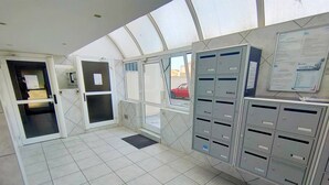 A reception area with a glass door, a tiled floor, and metal filing cabinets. - Appartement T2 vue Mer, Moderne, Clim 3 Etoiles Parking 4plmer53 (CANET PLAGE)