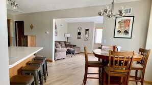 A spacious kitchen with a central island, bar stools, and a dining area with wooden chairs and a table.