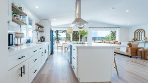 Una cocina moderna con armarios blancos, una isla central y vistas a un balcón.