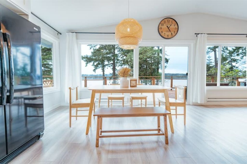 Una cocina amplia con una isla grande, un refrigerador negro y una mesa de comedor de madera con sillas.