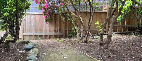Un jardín con un sendero empedrado, una cerca de madera y árboles en flor.