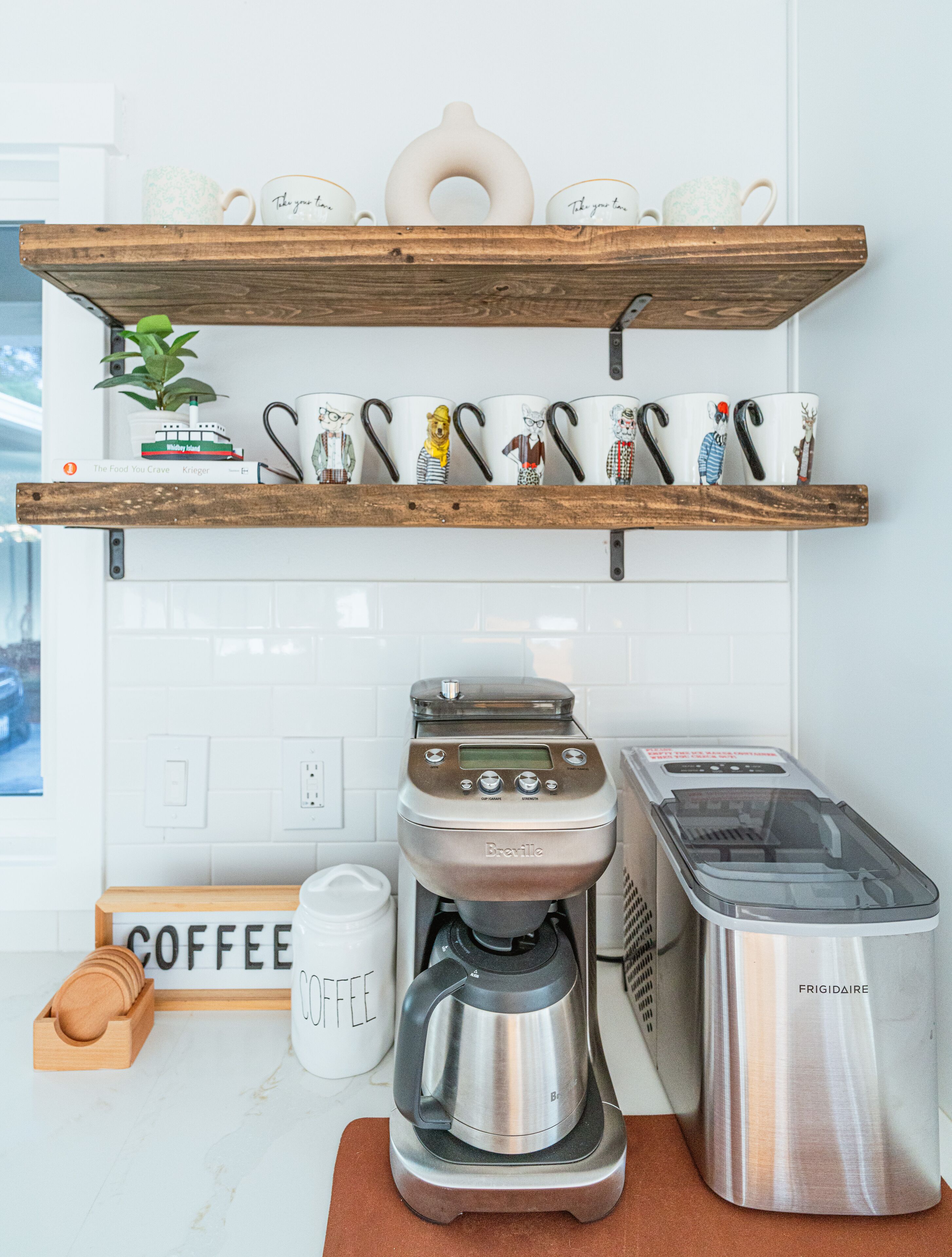 Une cuisine équipée d’une machine à café, d’un grille-pain et d’étagères où sont rangées des tasses.