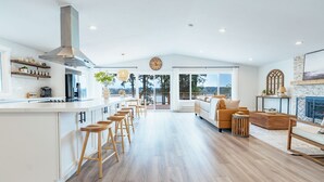 Una cocina amplia con una isla central, taburetes de bar y un gran ventanal con vistas panorámicas.