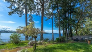 Une propriété paisible située au bord d’un lac, avec une pelouse bien entretenue, de grands arbres et une vue sur l’eau.
