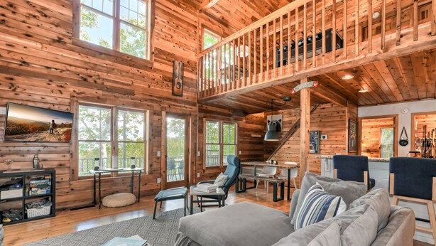 A spacious cabin with a loft bedroom, a dining area, and a cozy living room with a fireplace.