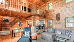 A spacious cabin interior with a loft bedroom, a dining area, and a living room furnished with modern decor.