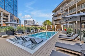 A rooftop pool with lounge chairs, umbrellas, and a view of surrounding buildings. - Hyve - Boho Bliss - 3 Bedroom - Located In SOBRO (Nashville)