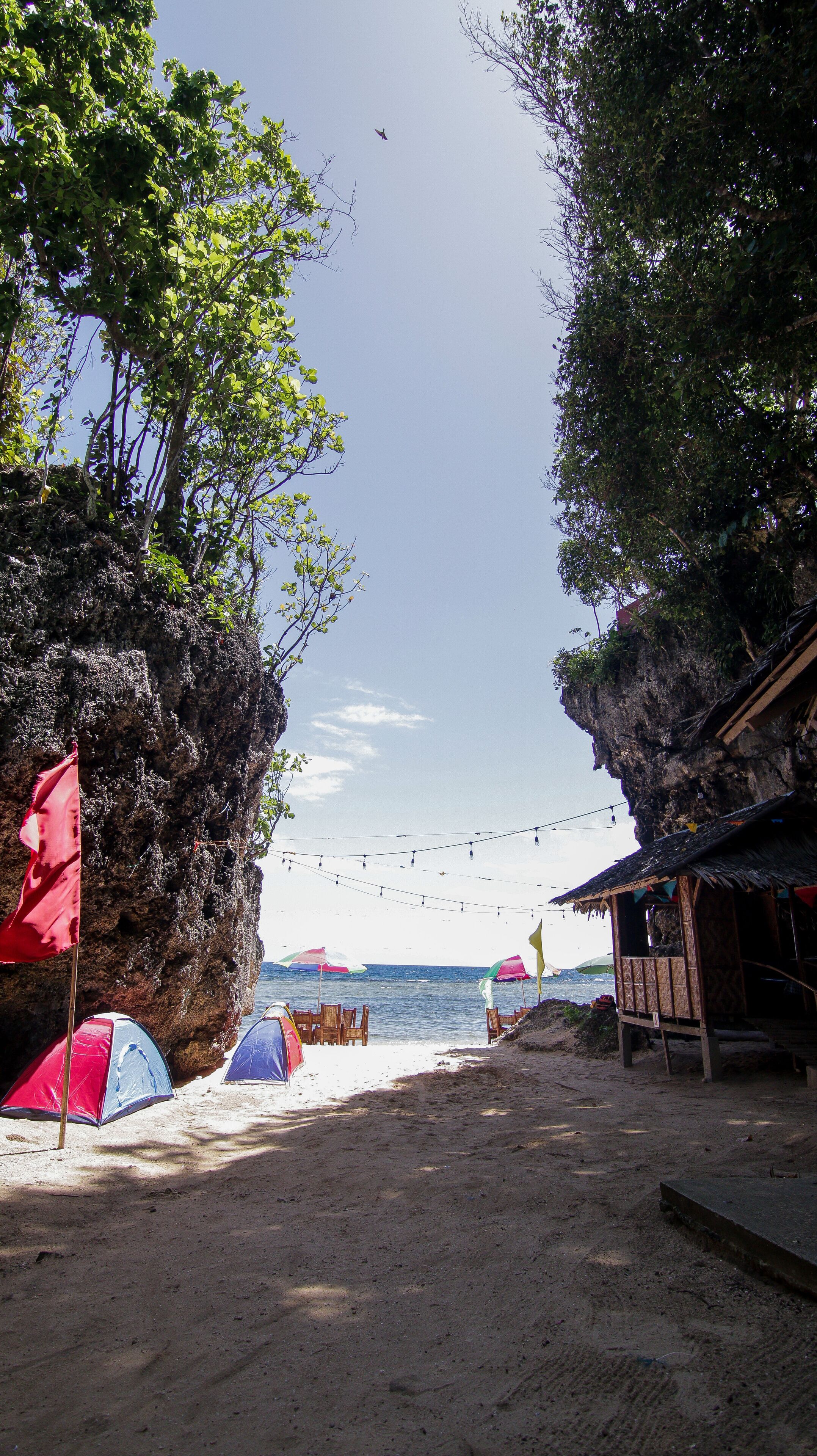 A beach with tents, a wooden structure, and string lights.