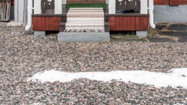 Een houten huis met een witte veranda en een bruine deur.