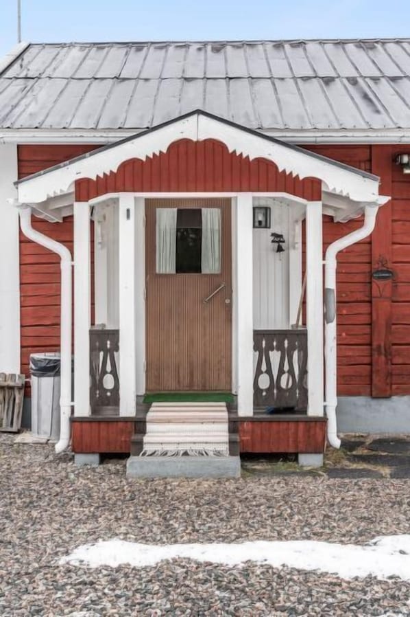 A wooden house with a white porch and a brown door.