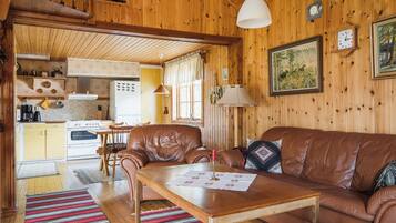 Interior acogedor de una cabaña con detalles de madera, una zona de comedor y una cocina.