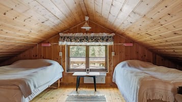 Un dormitorio acogedor en el ático con dos camas, un escritorio y una ventana con vistas.