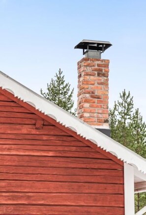 A red wooden building with a brick chimney.