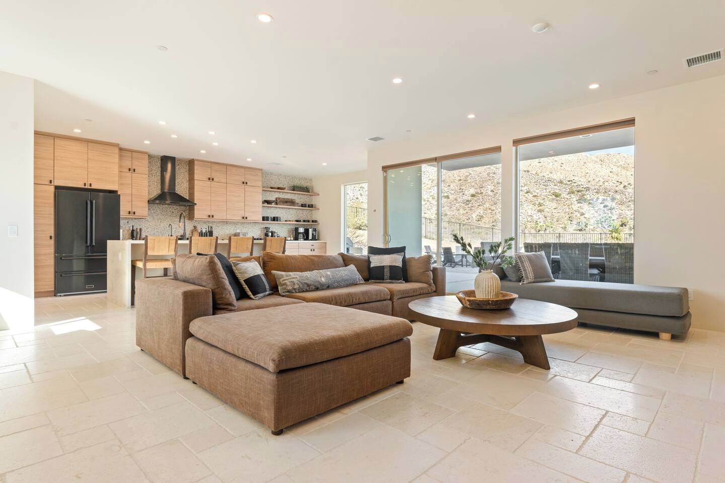 Ein modernes Wohnzimmer mit einem Ecksofa, einem Couchtisch und einer Küchenzeile mit Holdekor und einem eingebauten Backofen.