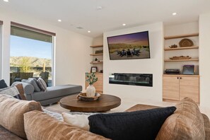 A modern living room with a sofa, coffee table, and a flat-screen TV mounted on the wall.