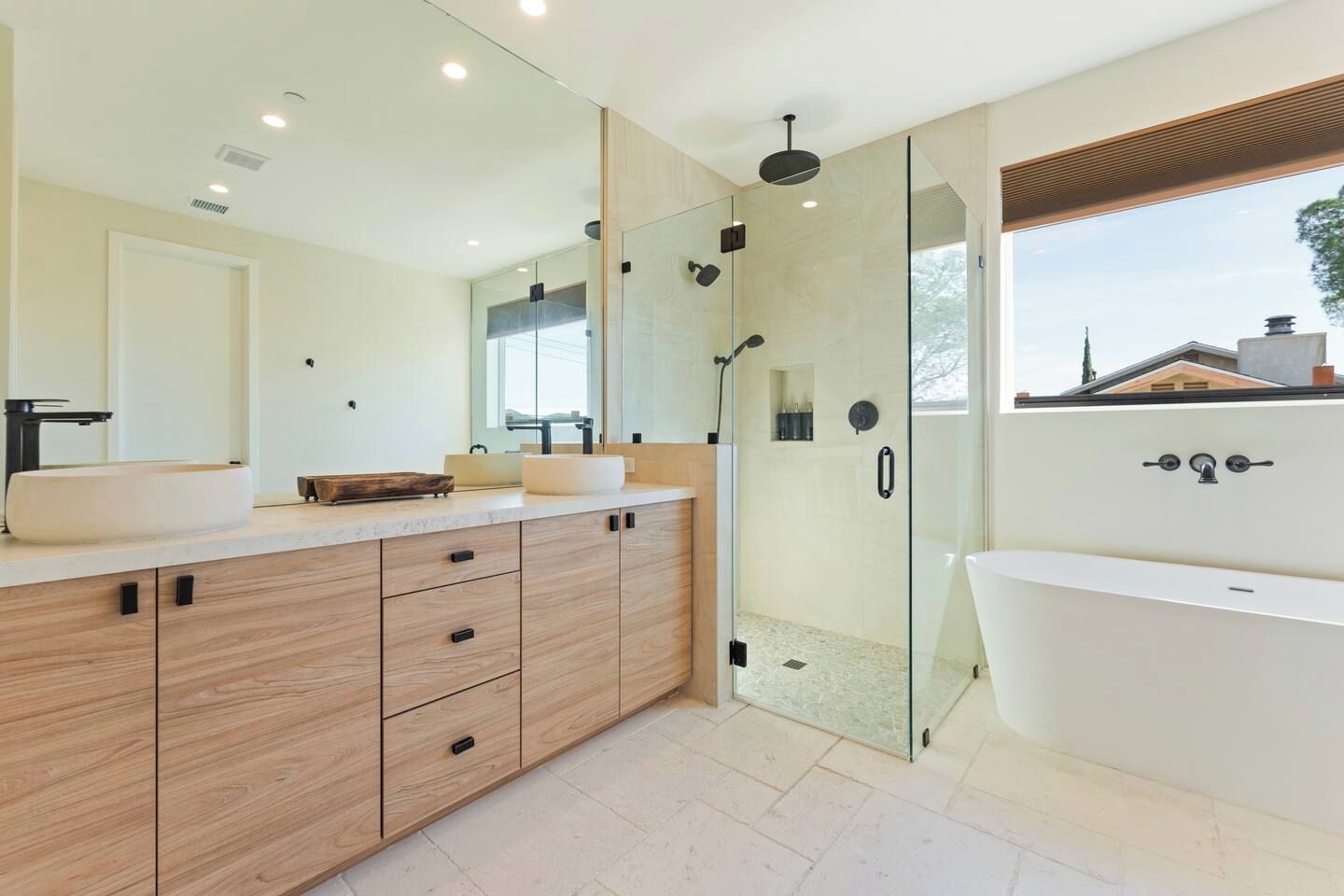 Un baño moderno con un espejo grande, una bañera independiente y una zona de ducha con paredes de vidrio.