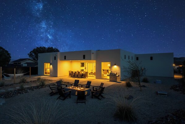 A modern house with an open patio, outdoor seating, and a fire pit.