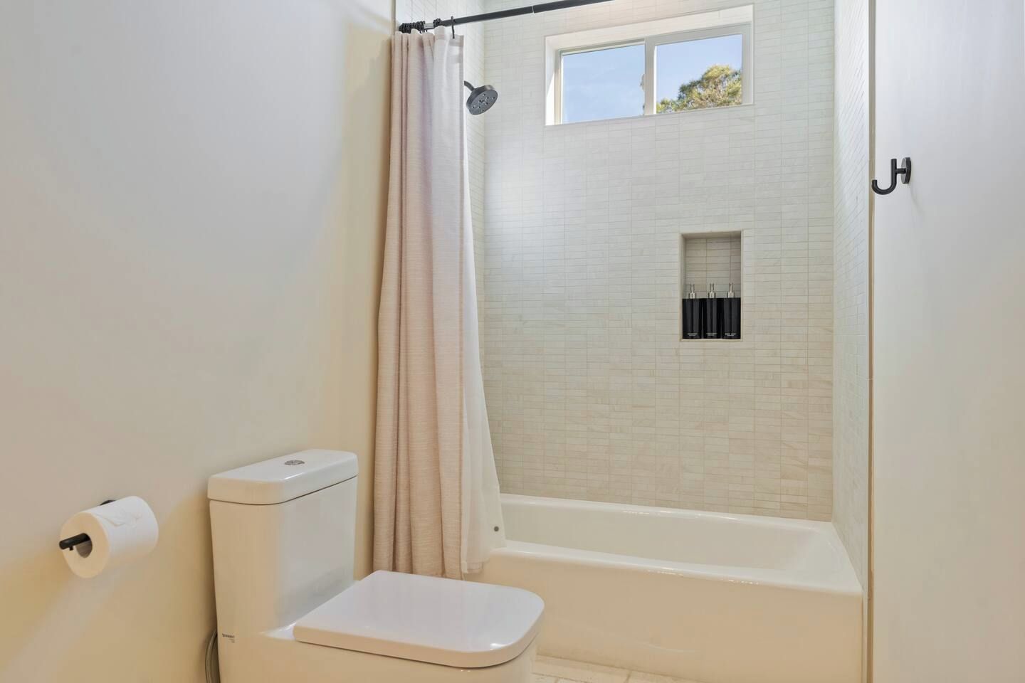 Une salle de bain avec une douche, des toilettes et une fenêtre.